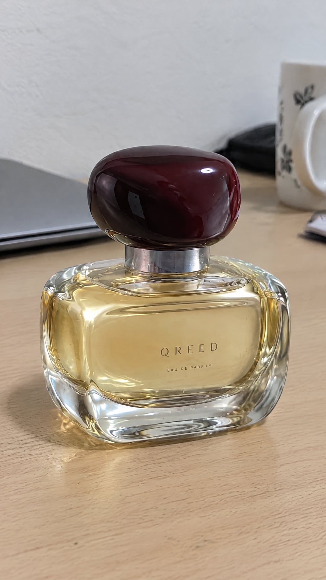 The QREED perfume in a phone photo on a desk